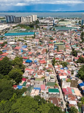 Büyük bir gecekondu kolonisi sanayi bölgeleri, varlıklı bir alt bölge ve Metro Manila otoyolu arasına sıkışmış. Arka planda Laguna Gölü.