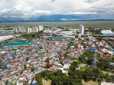 Büyük bir gecekondu kolonisi sanayi bölgeleri, varlıklı bir alt bölge ve Metro Manila otoyolu arasına sıkışmış. Arka planda Laguna de Bay.