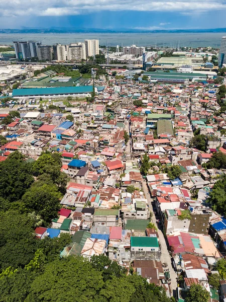 Büyük bir gecekondu kolonisi sanayi bölgeleri, varlıklı bir alt bölge ve Metro Manila otoyolu arasına sıkışmış. Arka planda Laguna Gölü.