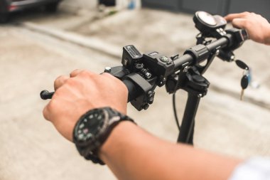 Bir adam elektrikli scooter kullanıyor. Ellerin ve gidonların kapatılması.