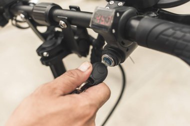 Bir adam elektrikli scooter 'ı anahtarla çalıştırıyor. E-motor ateşleme sistemi.
