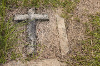 Yerdeki eski bir beton haç işaretlenmemiş bir mezarı ya da toprağın altındaki bir yeri işaret ediyor. Filipinler 'de bir halk mezarlığında..
