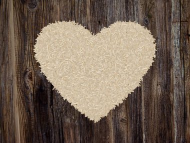 Rice grains shaped like a heart on a dark wood background.