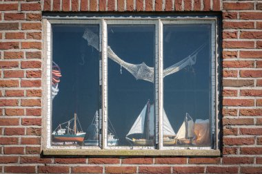 STAVOREN, FRIESLAND, NETHERLANDS - 23 HAZİRAN 2020: Gemi modelleriyle dekore edilmiş tuğla ev penceresi