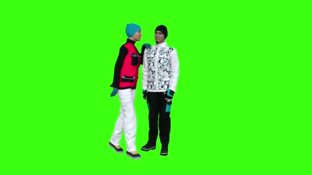 Een meisje in de winter kleding kust een jongen, groene achtergrond — Stockvideo
