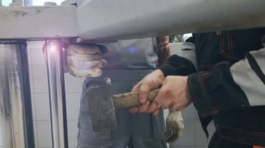 Usta atölyede çekiçle vurur.