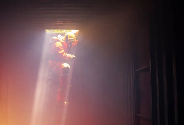 A firefighter in suit and helmet is climbing down the stair with fire to helping the victim.