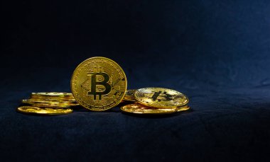 Golden bitcoin in the middle of pile, Bitcoin on dark blue background, Background with ray of light.