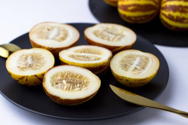 Vietnam kavunu yaklaş. Kesilmiş gurme minyatür tropikal meyve ve bıçağı siyah bir tabakta. Seçici odak