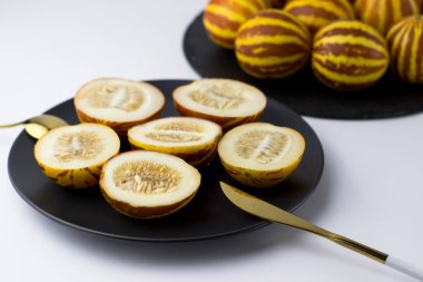 Vietnam kavunu yaklaş. Kesilmiş gurme minyatür tropikal meyve ve bıçağı siyah bir tabakta. Seçici odak