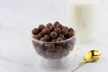 Kahvaltı gevreğini yakından çek. Beyaz mermer bir masada bir kase mısır gevreği.