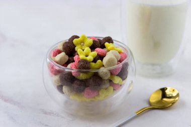 Kahvaltı gevreğini yakından çek. Beyaz mermer bir masada bir kase mısır gevreği.