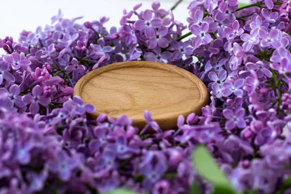 Wooden stand surrounded by lilacs. Wooden round background