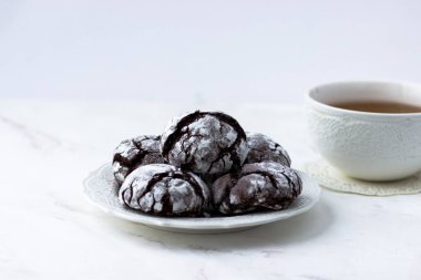 Kurabiyeler beyaz mermer masada çatırdıyor. Bisküvi ve bir fincan çay.