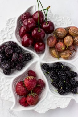Beyaz arka planda böğürtlen plakası. Çilek, bektaşi üzümü, kiraz, ahududu ve dut.