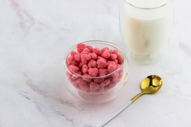 Çilek aromalı kahvaltı gevreği. Beyaz mermer bir masada bir kase abur cubur.