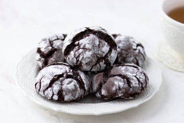 Kurabiyeler beyaz mermer masada çatırdıyor. Bisküvi ve bir fincan çay.