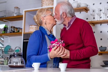 Mutfaktaki mutlu son sınıf çifti. Koca, sevgililer gününde ya da evlilik yıldönümlerinde karısını bir hediye ve öpücükle tebrik eder..