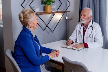 Deneyimli bir doktor, yaşlı bayan hastasıyla özel tıbbi dosyasını tartışıyor. Orta yaşlı bir kadın doktorunu kontrol ediyor ve sağlık ve sağlık sigortası hakkında danışmanlık yapıyor..