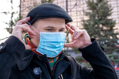 Koruyucu maskesini takan genç bir adam. Açık havada. Coronavirus koruma tedbirleri.