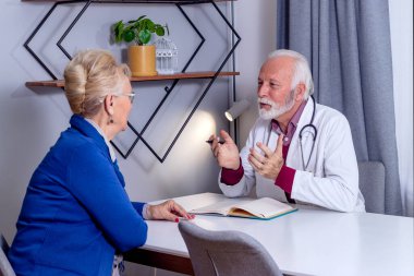 Deneyimli bir doktor, yaşlı bayan hastasıyla özel tıbbi dosyasını tartışıyor. Orta yaşlı bir kadın doktorunu kontrol ediyor ve sağlık ve sağlık sigortası hakkında danışmanlık yapıyor..