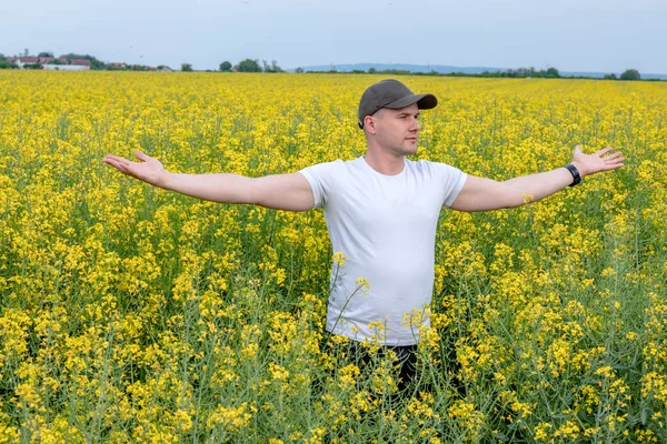 Yağ tohumu tarlasında dikilen bir çiftçi, iyi bir ürün için yağmur umuduyla kollarını açıyor. Verim tahmini için tarım ve hava tahmini arasındaki ilişki.