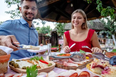 Geleneksel yemeklerle dolu güzel bir açık hava restoranında öğle veya akşam yemeği yiyen genç ve mutlu bir çift..