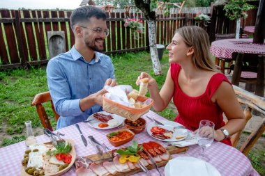 Geleneksel yemeklerle dolu güzel bir açık hava restoranında öğle veya akşam yemeği yiyen genç ve mutlu bir çift..