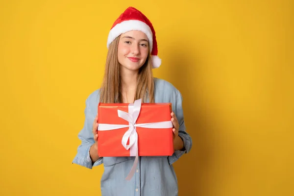 Junge Lächelnde Frau Mit Weihnachtsmütze Hält Weihnachtsgeschenkbox Isoliert Über Gelbem — Stockfoto