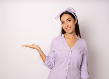 İzole edilmiş arka planda gülümseyen genç bir kadın elinde bir şeyle ürün sunumu yapıyor..