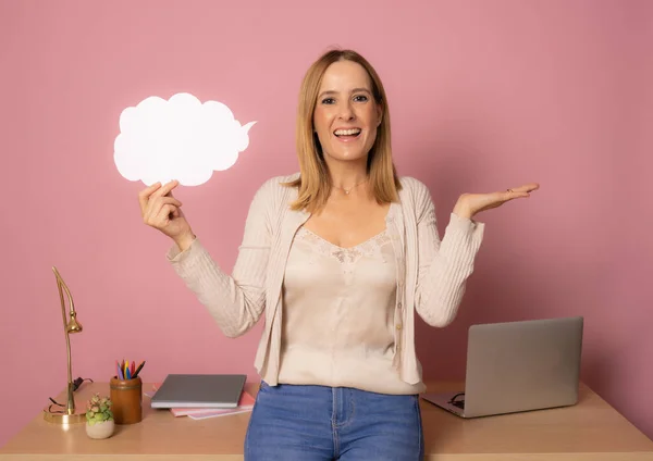 Young happy woman at work place holding paper cloud isolated over pink background.