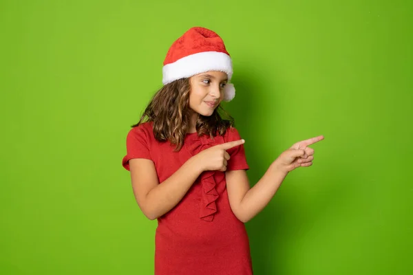 Menina Santa Chapéu Apontando Dedos Lado Isolado Sobre Fundo Verde — Fotografia de Stock