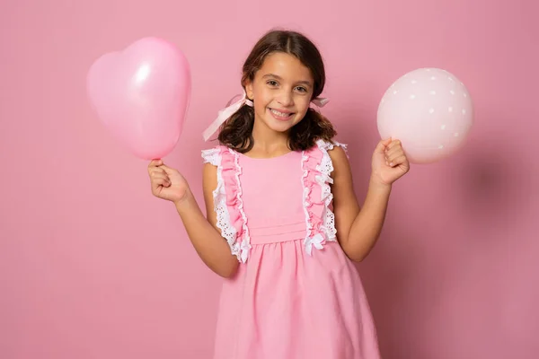 stock image Little smiling girl with balloons isolated over pink background. Celebration concept.