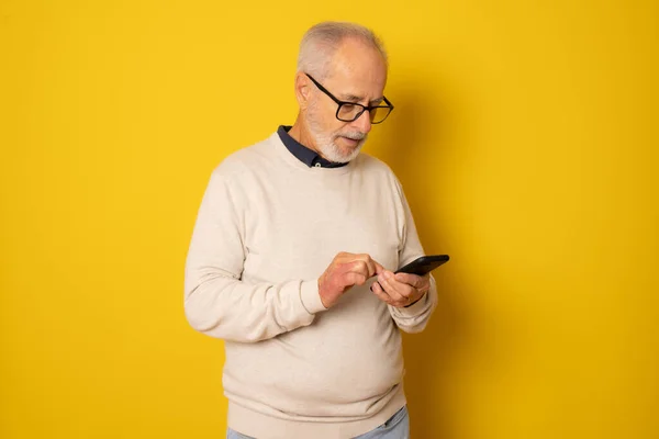 Homem Sênior Usando Smartphone Isolado Sobre Fundo Amarelo — Fotografia de Stock