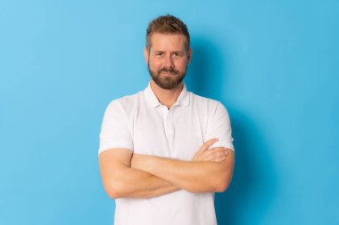 Kolları bağlı ve gülümseyen sıradan bir adam mavi arka planda soyutlanmış..