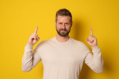 Gülümseyen sakallı bir adamın portresi sarı arka planda izole edilmiş fotokopi alanını işaret ediyor.