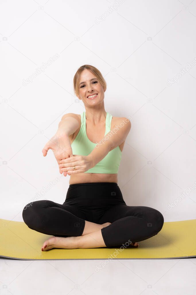 Young sport woman sitting on the floor doing stretching isolated over white background.
