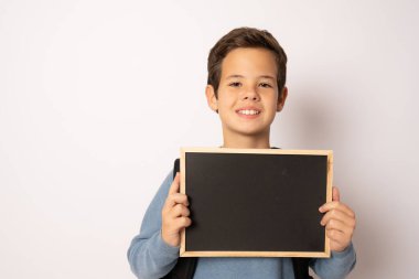 Beyaz arka planda izole edilmiş tebeşir tahtası tutan okul çocuğu.