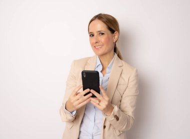Gülümseyen iş kadını beyaz arka plan üzerinden akıllı telefon kullanıyor..