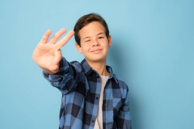 Ekose gömlekli sevimli çocuk mavi arka planda izole edilmiş 