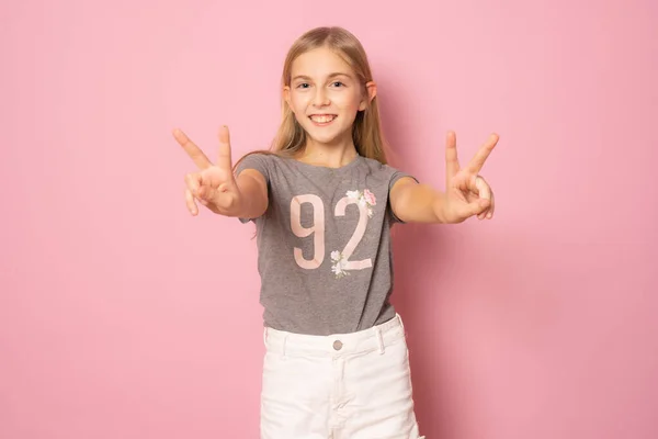 Happy Cute Little Girl Stoi Pokazując Symbol Pokoju Różowym Tle — Zdjęcie stockowe