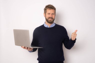 Genç, gülümseyen, elinde dizüstü bilgisayarla beyaz arka planda duran yakışıklı bir adam..