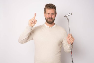 Beyaz arka planda tek başına golf oynayan yakışıklı bir adam..