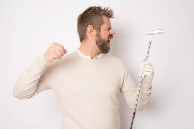 Kızgın yüzüyle golf oynayan yakışıklı genç adam beyaz arka planda tek başına duruyor..