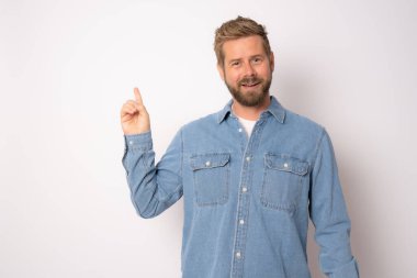 Kot gömlekli genç adam beyaz arka planda parmak tarafını gösteriyor..