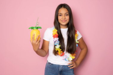 Yazlık kıyafetli güzel bir kız pembe arka planda ananas suyu tutuyor..