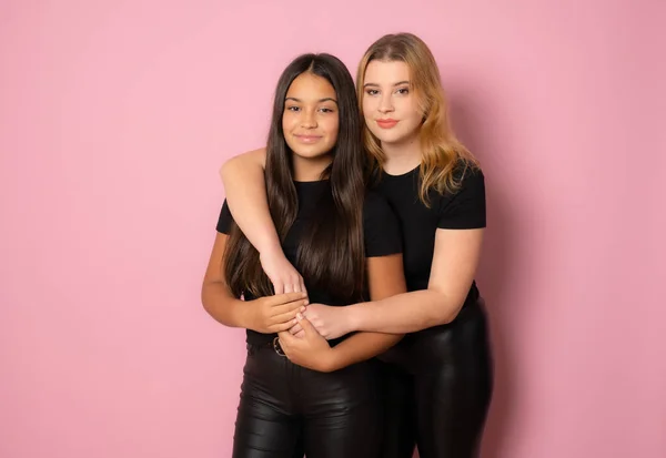 Две Девушки Черном Позируют Вместе Стоя Розовом Фоне — стоковое фото
