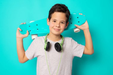 Yeşil arka planda tek başına duran kaykaylı çocuk..