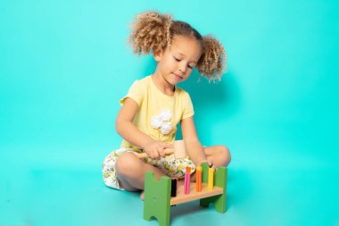 Yeşil arka planda renkli oyuncaklarla oynayan sevimli bir çocuk.