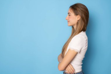 Beautiful girl wearing casual clothing posing with arms folded isolated over blue background.